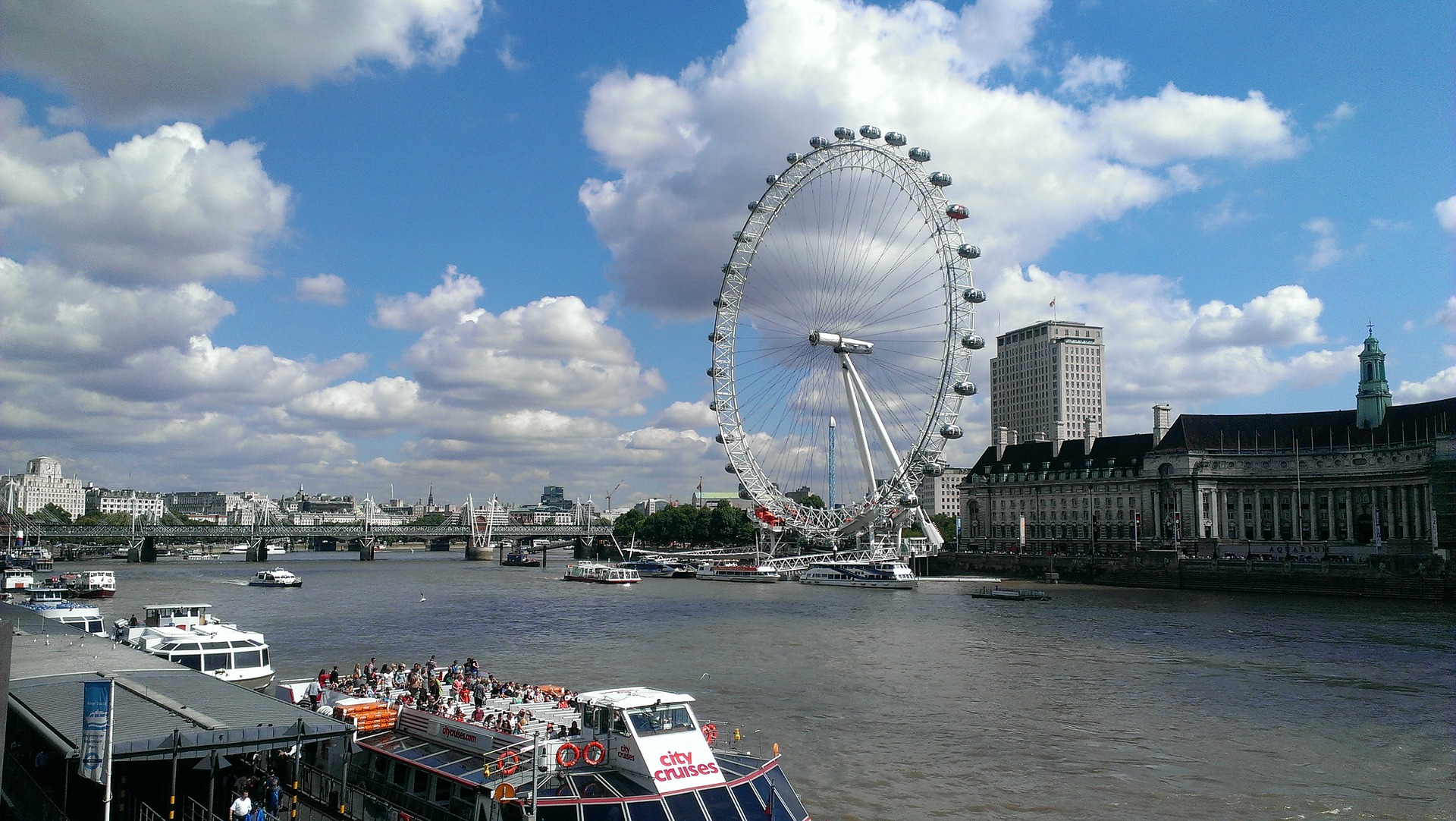 River boats on the Thames River and London Eye, London, UK